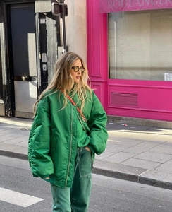 Street style view of a green oversized bomber jacket with matching green knitwear