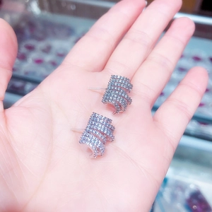 Close-up of geometric spiral S925 silver stud earrings with inlaid zircon on a hand