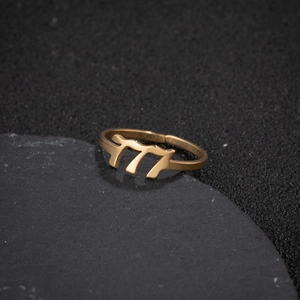 Macro detail of gold-plated stainless steel ring featuring cutout 777 angel numbers