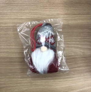 Detail of gray knitted gnome ornament with white beard in clear protective packaging