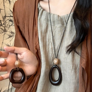 Retro geometric wood resin pendant necklace with beige bead on black cord shown on a model