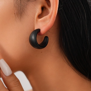 Close-up of a matte black acrylic C-shaped chunky earring worn by a female model