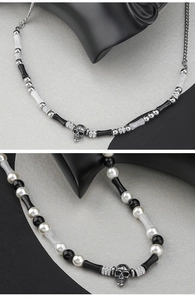 Detail of silver skull pendants on mixed black, white, and pearl beaded necklaces