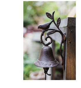 Detailed close-up of a rustic cast iron garden doorbell with a bird ornament and textured finish