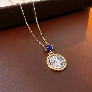 Detailed close-up of blue gemstone and silver portrait coin pendant on a gold necklace