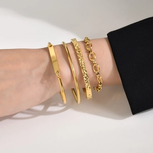 Set of four gold stainless steel bracelets with hammered texture and smooth finish