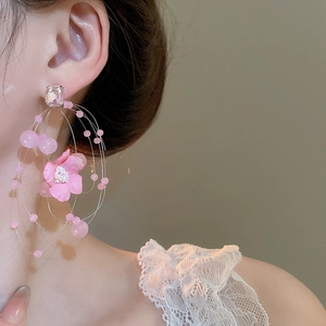 Close-up of pink fabric flower earrings with beaded tassels on a model for a sweet look