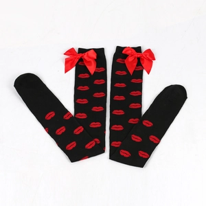 Detail of black over-the-knee socks with red lip patterns and festive bows