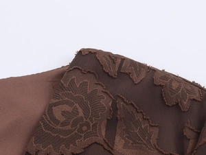 Gros plan détaillé du tissu jacquard marron foncé avec motifs de feuilles et franges