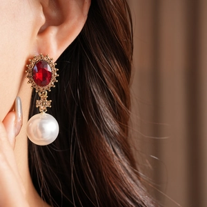 Vue détaillée de boucles d'oreilles baroques avec pierre rouge et perle sur le mannequin