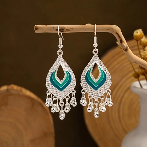 Macro detail of bohemian silver earrings with teal enamel and metallic tassels