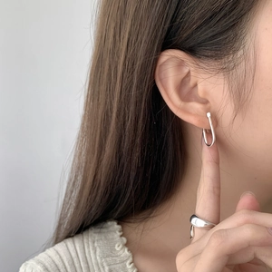 Detail of silver U-shaped earring and irregular polished ring on a model