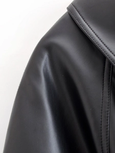 Detailed macro view of the stitching and leather texture on a black cropped jacket