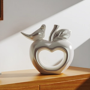 Vogel auf Herzskulptur mit Perlenfinish auf Holztisch bei natürlichem Licht