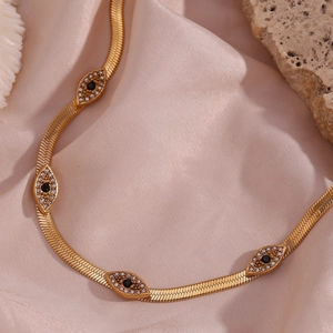 Detail of 18K gold-plated snake chain necklace with sparkling zircon evil eye charms