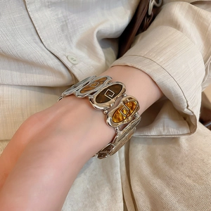 Detail view of retro silver stretch bracelet with amber resin oval inlay on a linen sleeve
