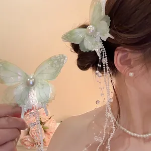 Elegant butterfly hair clip with green lace wings and long pearl tassels shown on a model