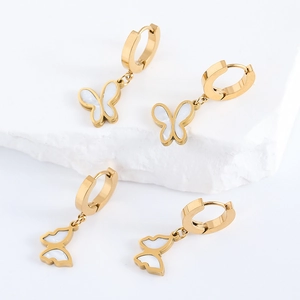 Golden butterfly earrings with white pearl inlay set on white stone background