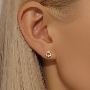 Close-up of golden floral wreath earring with white zircon inlay on model ear
