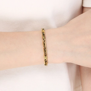 Gros plan d'un bracelet gourmette en acier inoxydable doré sur le poignet d'un mannequin