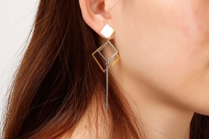 Detail of geometric rhombus dangle earrings in two-tone gold and silver on a model