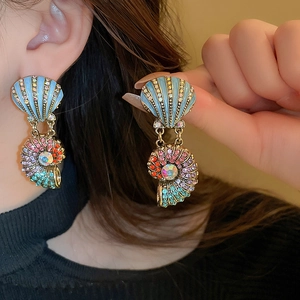 Nahaufnahme von Muschelohrringen aus Gold mit blauem Emaille und bunten Strasssteinen am Model