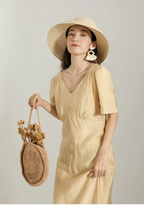 Detail of elegant cream v-neck maxi dress with silky texture and matching accessories