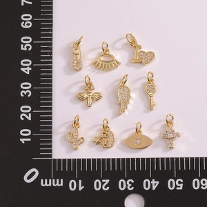 Macro shot of 10 assorted gold-plated cubic zirconia charms with measurement scale