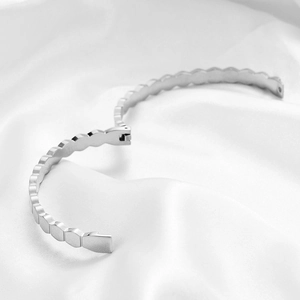 Close-up of hexagonal honeycomb bracelet with polished silver finish on silk