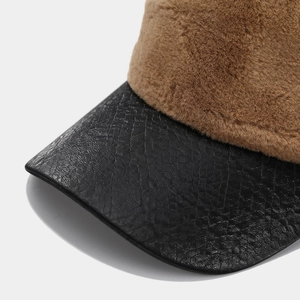 Macro detail of brown plush faux fur and black snakeskin texture leather hat brim