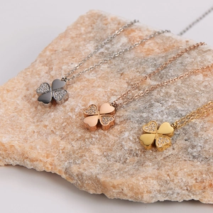 Three minimalist clover leaf necklaces in silver, rose gold and gold finishes on a stone
