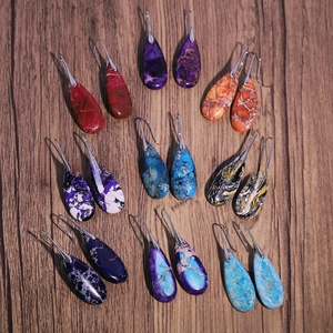 Detail view of teardrop natural stone earrings in various colorful textures on wood