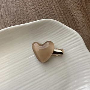 Detail of light brown translucent heart hair clip on a white ceramic tray