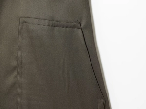 Nahaufnahme von olivgrünem Köperstoff mit detaillierter Taschennaht und Textur
