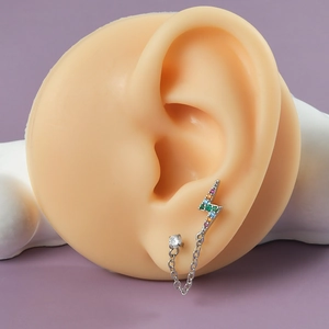 Detailed view of lightning stud earring with rainbow cubic zirconia and steel chain on ear