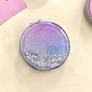 Detailed macro view of round folding makeup mirror with purple glitter and silver stars