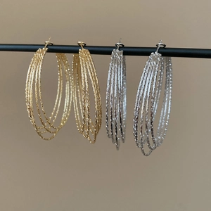 Detail of layered textured hoop earrings in gold and silver finish on a display bar