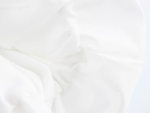 Dettaglio della trama del tessuto bianco traforato e cuciture sulla maglia con scollo a V
