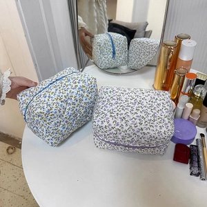 Floral print cotton makeup bags in blue and purple on a white vanity table