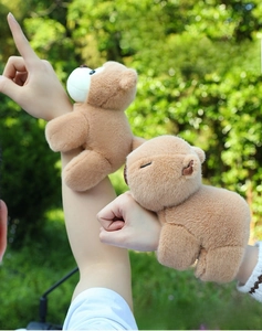 Outdoor shot of plush panda and capybara slap bracelets worn on a person's wrist