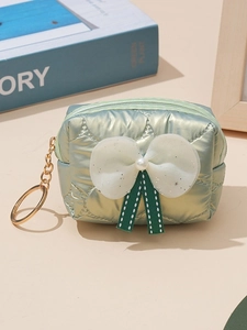 Mint green quilted satin bow coin purse with pearls and gold keychain on a desk