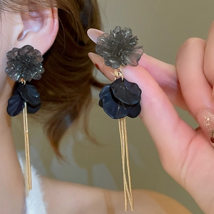 Detail shot of acrylic flower earrings with long gold tassels and dark grey petal accents