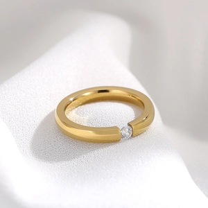 Detailed view of a minimalist gold zircon ring on a white knitted fabric texture