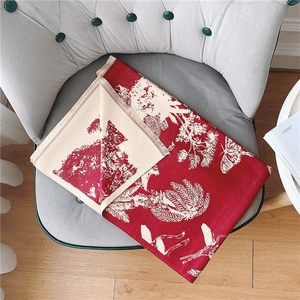 Détail d'une écharpe rouge en imitation cachemire avec motifs animaux et franges