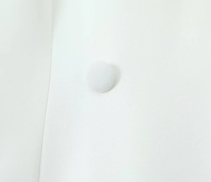 Detailed view of a white fabric-covered button on a high-quality plain weave blazer fabric