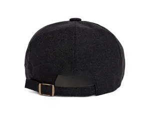 Detail view of the black newsboy hat's back with a bronze metal adjustable buckle strap