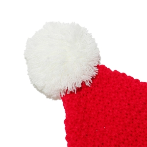 Dettaglio ravvicinato del pompon bianco soffice e della trama a maglia rossa del cappello di Natale