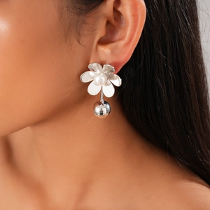 Close-up of a floral pearl earring with a silver metallic ball on a female model