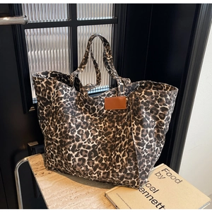 Detail of leopard print canvas tote with brown leather patch and metal rivet accents
