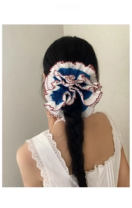 Macro detail of a large blue and white lace scrunchie on a braided hairstyle